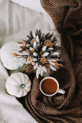 Coffee cup with flowers and pumpkins on a cozy plaid. Autumn still life. Breakfast in bed. Good morning. Stylish autumn flat lay. 