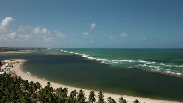 This is the beach of Gunga, in Brazil. 
There is a rock formation that stops the waves from coming to the beach.