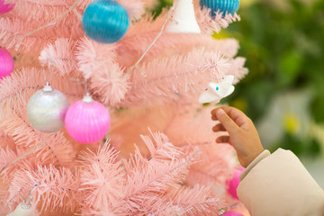 Kid hand holding bauble for Christmas tree pink color. Merry Christmas and Happy New Year 2020. Xmas concept. Side view. Holiday background