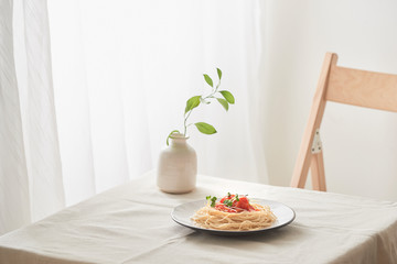 handmade pasta with ragout sauce on plate on vintage white table with colander and flowers