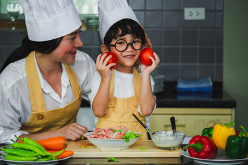 Asian woman young mother with son boy cooking salad mom sliced vegetables food son tasting salad dressing vegetable carrots and tomatoes bell peppers happy family cook food enjoyment lifestyle kitchen
