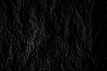 Dark black crumpled paper close up texture background