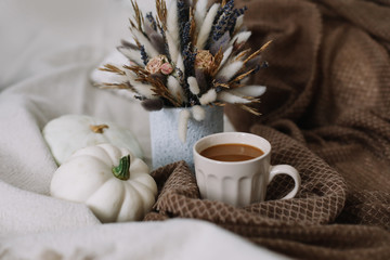 Coffee cup with flowers and pumpkins on a cozy plaid. Autumn still life. Breakfast in bed. Good morning. Stylish autumn flat lay. 