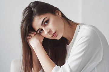 Fototapeta premium Beautiful portrait of gorgeous woman. Young brunette in the room with white walls and daylight that comes from the window