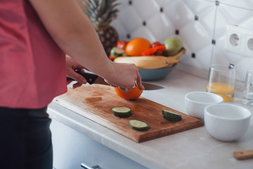 Cutting oranges. Girl in the modern kitchen at home at her weekend time in the morning
