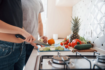 Fresh sliced fruits. Young couple in the modern kitchen at home at their weekend time in the morning