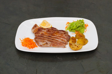 Juicy grilled meat steak with lemon, carrots, lettuce and potatoes.
