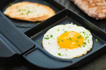 Lunch, grilled steak or cutlet, toast and egg on a black plate. The concept of healthy diet, diet, menu. Place for text with left, copy space.