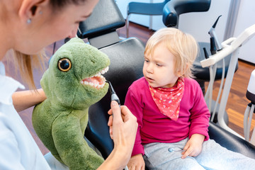 Little child in dentists surgery learning how to brush teeth