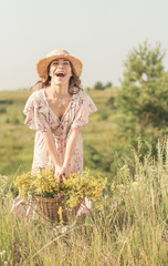 Obraz premium girl with a basket of flowers and a straw hat in a summer field