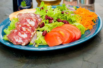 Salad with sausage, tomatoes, beans, carrots, spices, olive oil or sauce. Restaurant serving Italian food