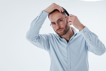 Getting prepared for the business meeting. Man in official clothes stands against white background in the studio