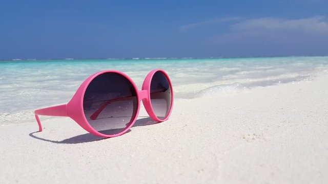 Pink sunglasses left on the sandy white beach at the Caribbean 4K footage