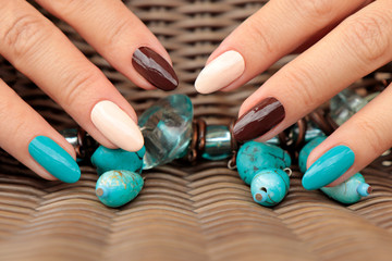 Fototapeta na wymiar Oval multicolored manicure on a woman's nails.Nail design with turquoise, brown, light beige nail Polish.