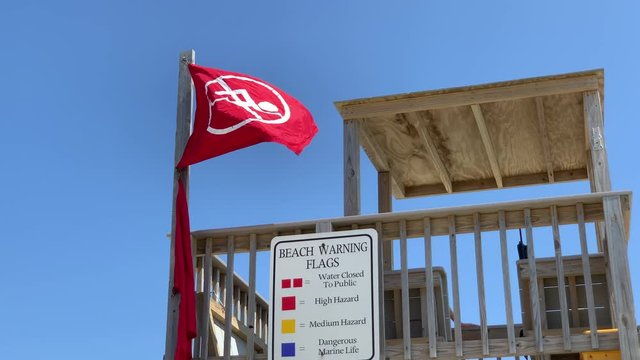 a no swimming flag flies from a lifeguard stand at the beach