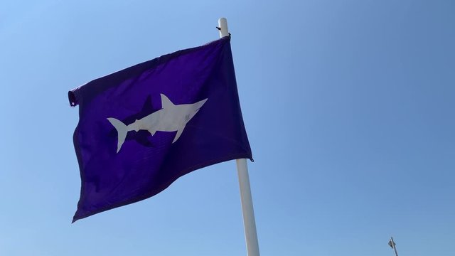 A shark warning flies at the beach in slow motion
