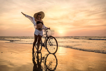 Happiness woman traveler with her bicycle walking on sea coastli