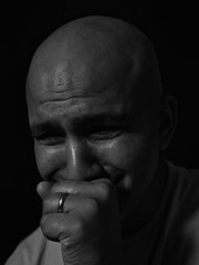 Black and white portrait of a bald headed man holding back tears