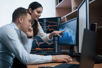 Girl is smiling, guy talks using the phone. Team of stockbrokers are having a conversation in a...