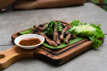 Sun dried Thai fried Beef Jerky meal Nua Dad Deaw served on wooden chopping board with spicy chilli...