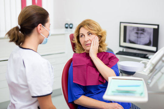 Attractive Mature Woman With Pain In Dentist Office With Doctor