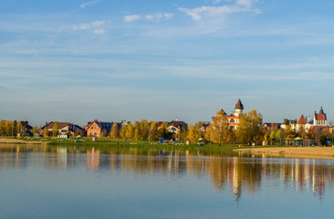A lake with blue water and sky. Beautiful houses and cottages on the horizon.