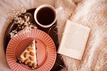 Good morning with hot black tea and chocolate cake with oprn book on knitted cloth close up. Top view. Breakfast time.