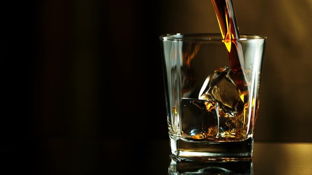 Super Slow Motion Macro Shot of Pouring Whiskey into Glass with Ice Cubes at 1000fps. Filmed on High Speed Cinema Camera in 4K.