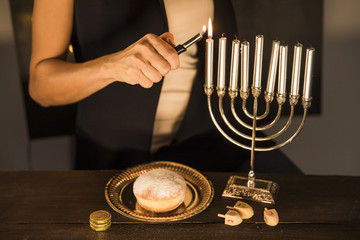 Crop woman lighting candles on menorah
