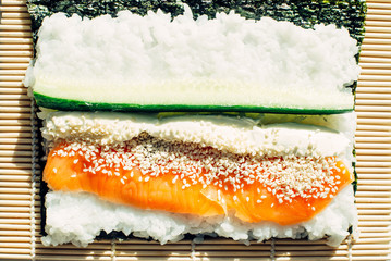 Cooked rice and fresh fish with sesame seeds on nori. Cooking sushi at home. Traditional japanese food.
