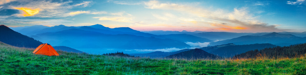 Orange tent on a plain in the mountains
