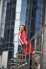 Looking at view. Adult pretty woman in warm red coat have walk in the city at her weekends time