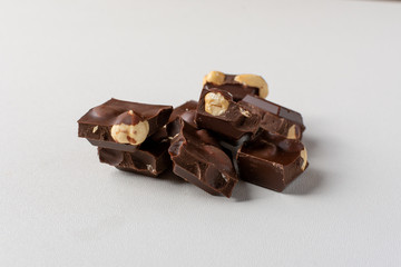 Dark chocolate on white background with whole hazelnuts