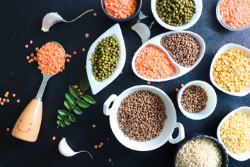 Composition of dry legumes. Assortment of colorful legumes in bowls. Lentils, Moth beans, Mung Beans, Masoor or red lentils, Split Chickpea, Toor Dal, Raw Split Mung Bean Lentils, Yellow Split.