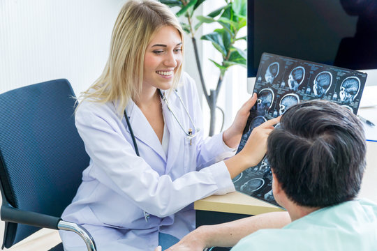 Caucasian female doctor showing Asian patient the film of MRI tomography scan of the brain.