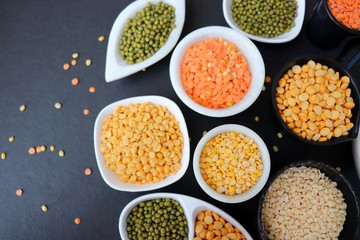 Composition of dry legumes. Assortment of colorful legumes in bowls. Lentils, Moth beans, Mung Beans, Masoor or red lentils, Split Chickpea, Toor Dal, Raw Split Mung Bean Lentils, Yellow Split.