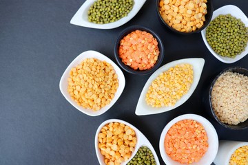 Composition of dry legumes. Assortment of colorful legumes in bowls. Lentils, Moth beans, Mung Beans, Masoor or red lentils, Split Chickpea, Toor Dal, Raw Split Mung Bean Lentils, Yellow Split.