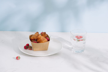 Croissant with raspberries. Raspberries with croissants. Croissant on a light background with raspberry berries