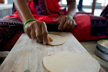 close up of old indian woman hands making fresh homemade rotis and chapati, a classic indian street food