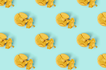 Pattern made of crushed yellow macaroons on pastel blue background. Creative layout.