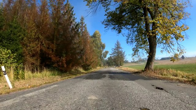 Autumn car drive in rural landscape. Car drive in fall landscape with fall colored trees and blue sky in sunny day. Countryside road. Fall concept