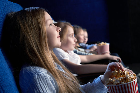 Beautiful girl sitting in cinema and watching film