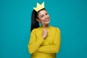 Young woman keeping paper crown and posing