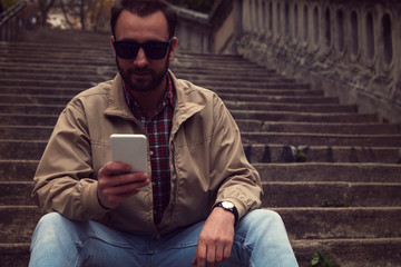 Handsome man using cellphone in European city.