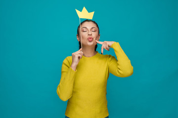 Brunette keeping paper crown and posing in studio