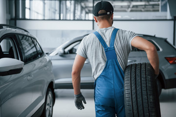 This needs to be taken away. Mechanic holding a tire at the repair garage. Replacement of winter...