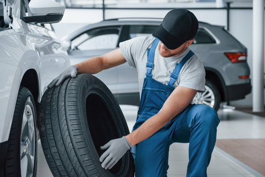 Fresh material. Mechanic holding a tire at the repair garage. Replacement of winter and summer tires