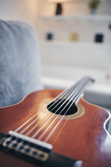 Acoustic guitar on a living room couch / sofa.