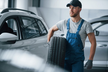 Feeling nice. Mechanic holding a tire at the repair garage. Replacement of winter and summer tires