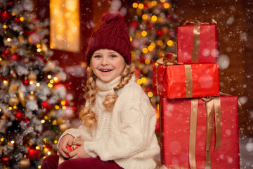 happy cheerful girl in a hat and with pigtails on the veranda of the house in anticipation of Christmas